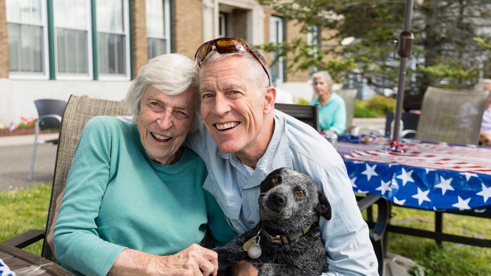 A resident in a light green sweater and a visitor with his dog.